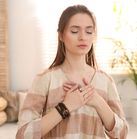 Femme en méditation avec les mains sur le cœur.